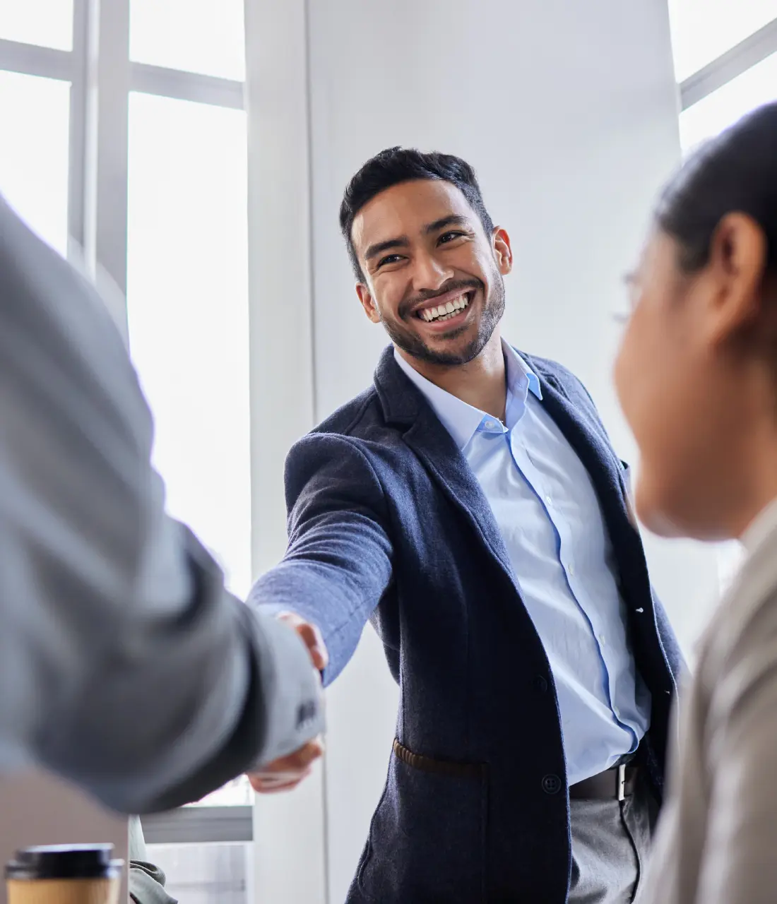 A man shaking hands with another person in front of him.