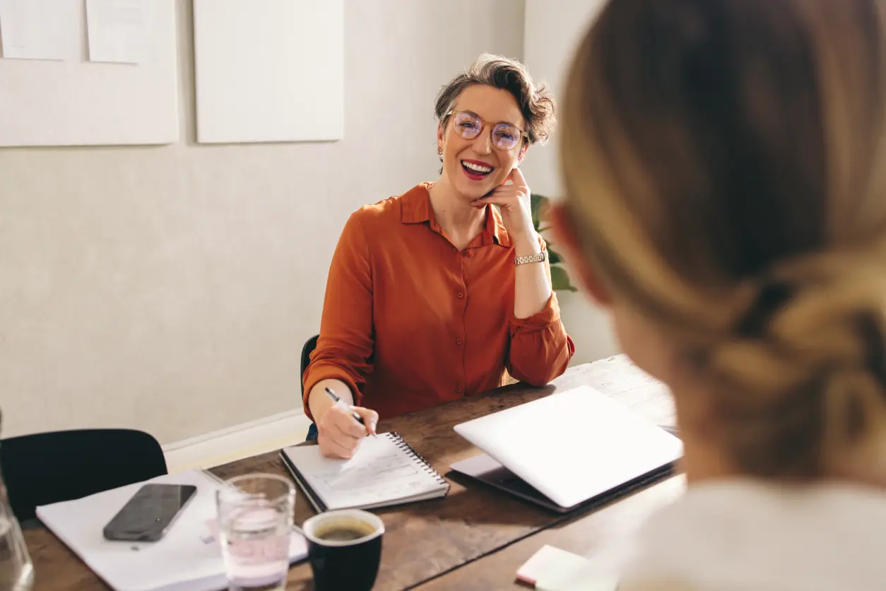A woman sitting at a table with papers and coffee.