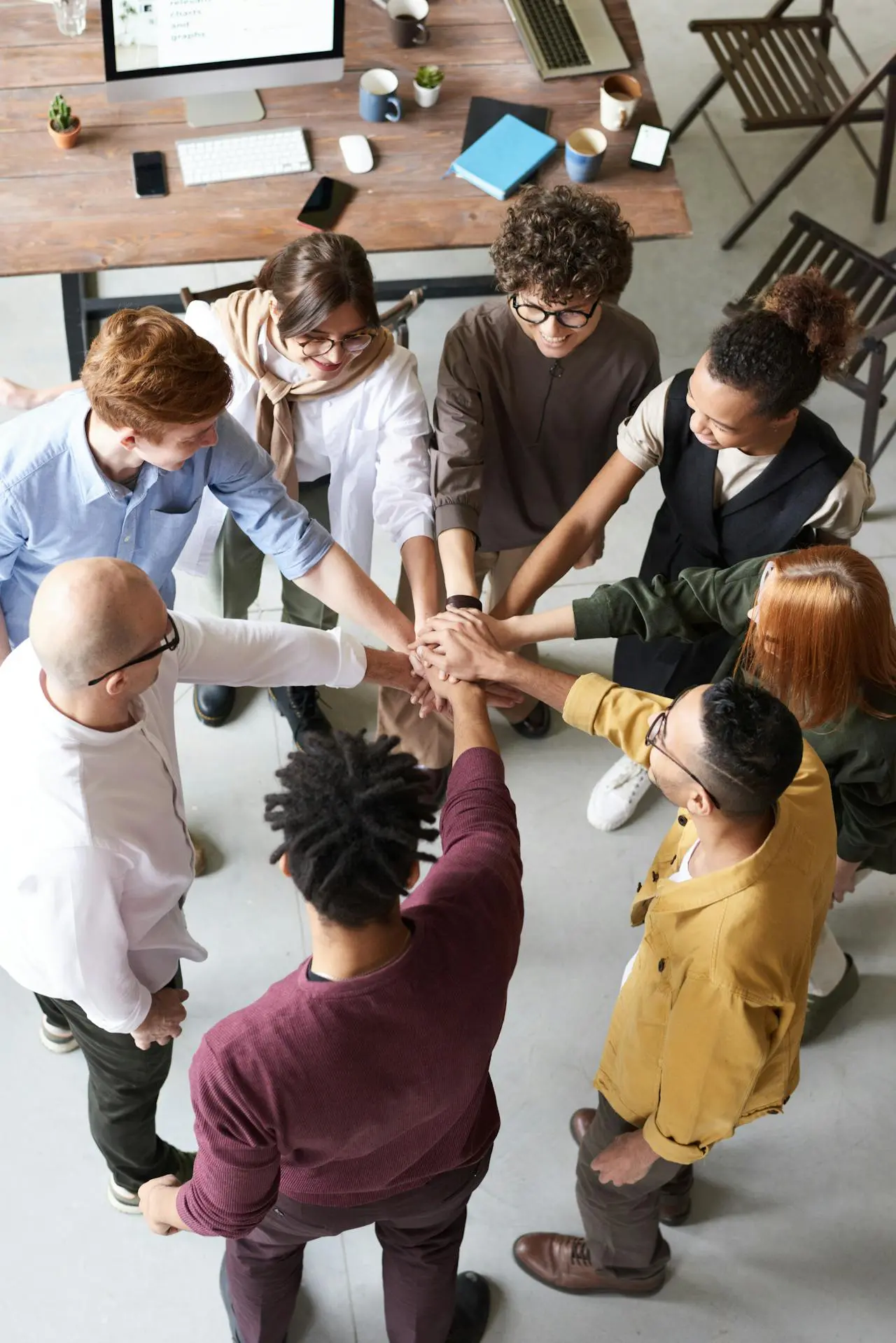 pexels-fauxels-3184423 A group of people holding hands in the middle of a circle.